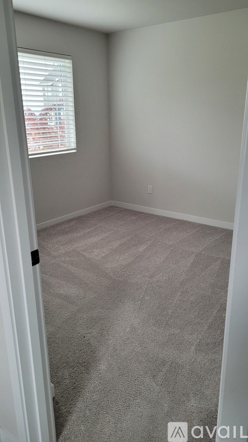 A room with a carpeted floor and a window with blinds.