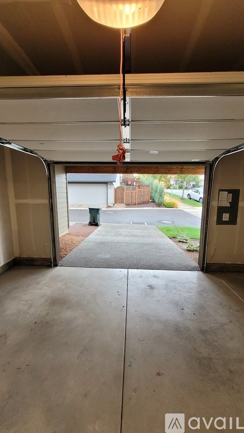 A garage with a concrete floor and a hanging light fixture.