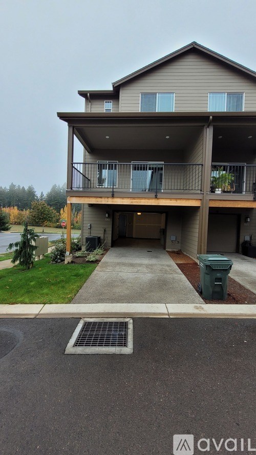 A two-story house with a balcony and a green trash can.
