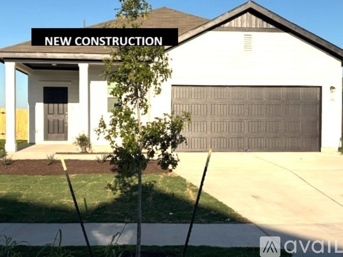A new construction house with a garage door and a tree in front.