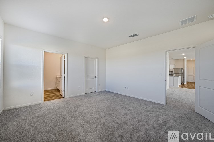 A spacious living room with a carpeted floor and white walls.