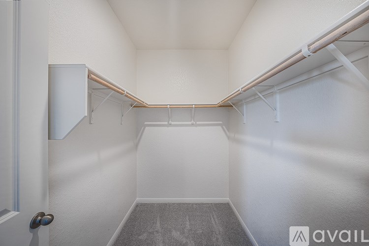 A small, empty room with a door on the left and a wall-mounted shelf on the right.