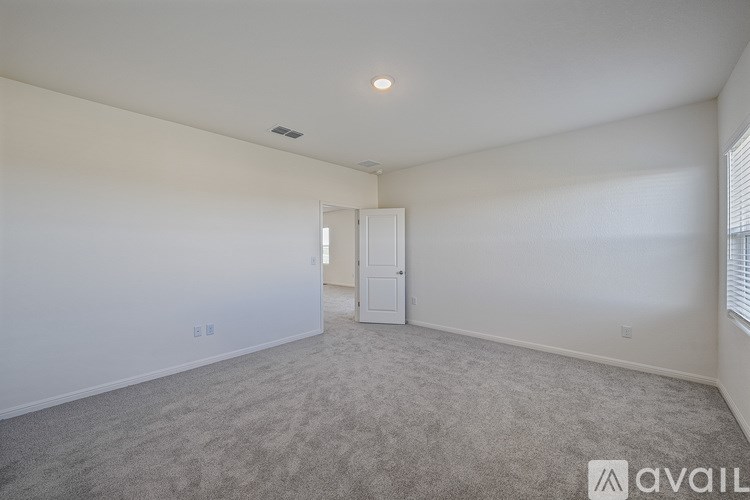A spacious room with a carpeted floor and a doorway leading to another room.