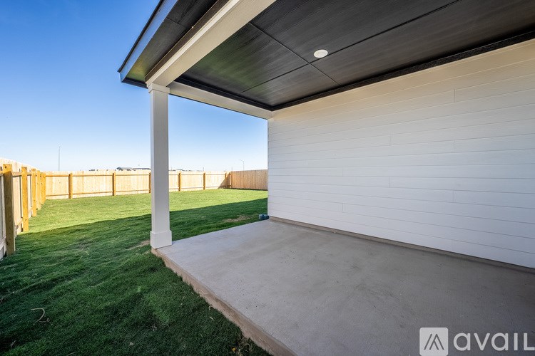 A patio area with a white wall and a concrete floor.