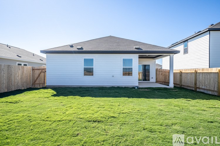 A white house with a brown roof and a green lawn in front.