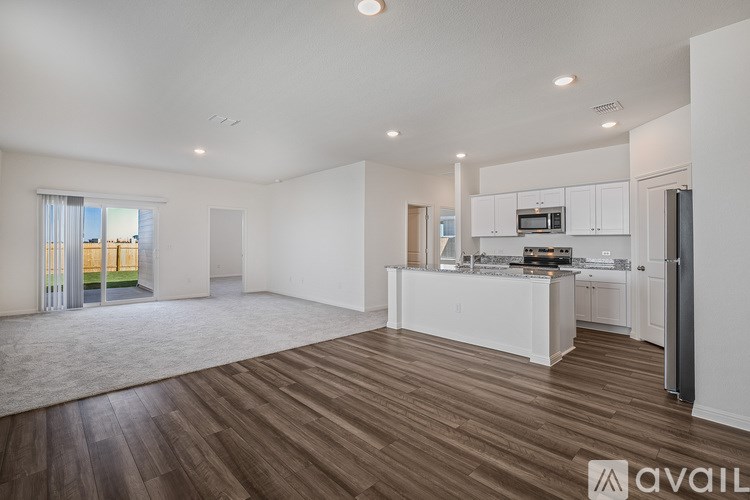 A white house with a brown roof and a fence in the front yard.