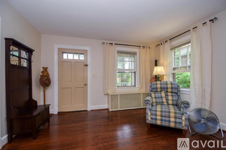 A room with a checkered chair and a fan.