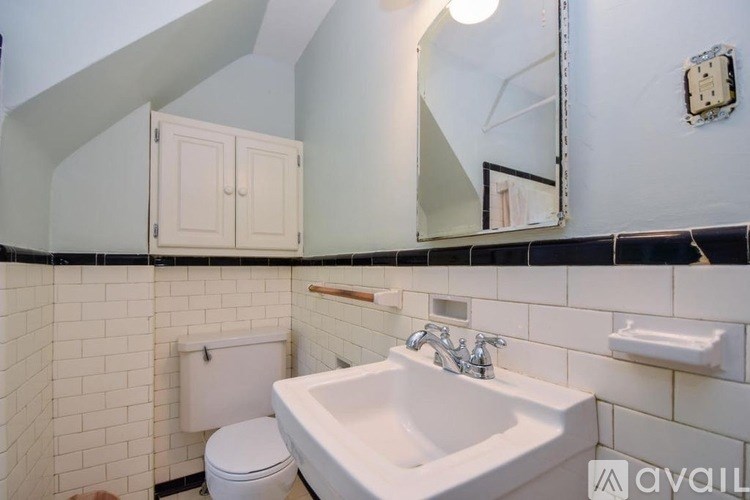 A bathroom with a white sink, toilet, and a mirror.