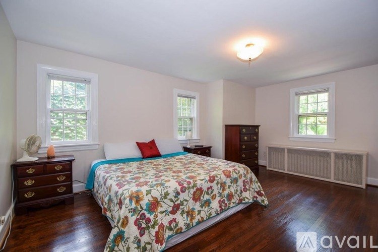 A bedroom with a floral bedspread and a window with blinds.