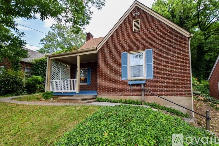 A red brick house with a porch and a green lawn in front.