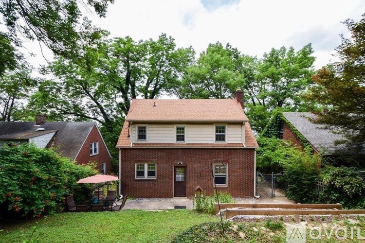 A house with a red door and a brown roof surrounded by greenery.