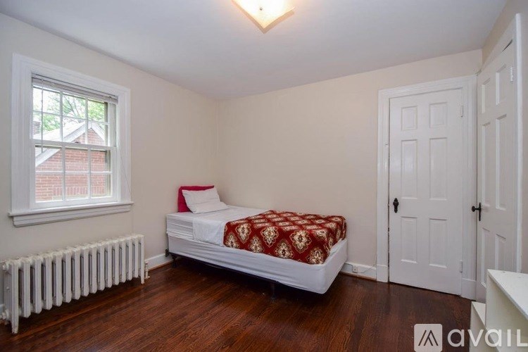 A bedroom with a bed, a window, and a radiator.