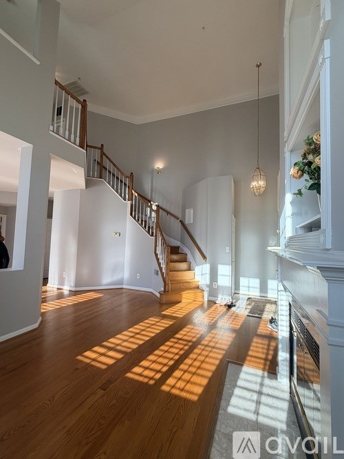 A large open living space with wooden floors and a staircase.