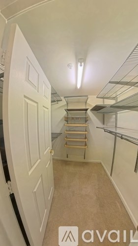 A narrow hallway with a white door on the left and a metal shelf on the right.