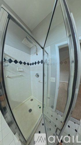 A bathroom with a glass shower door and a tiled floor.