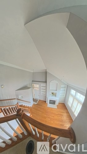 A staircase with a wooden handrail and white balusters leads to a landing with a white cabinet and a window.
