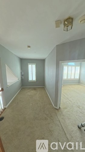 A room with a carpeted floor and a window with blinds.