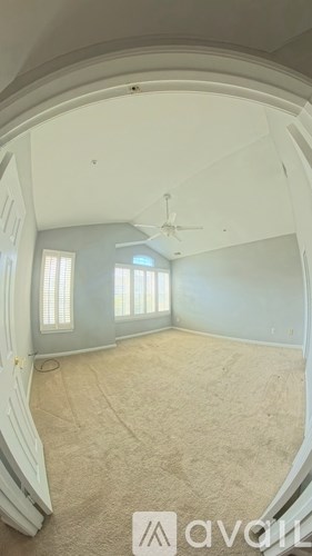 A room with a carpeted floor and a ceiling fan.