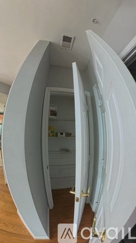 A white door is open to a small room with a wooden floor.