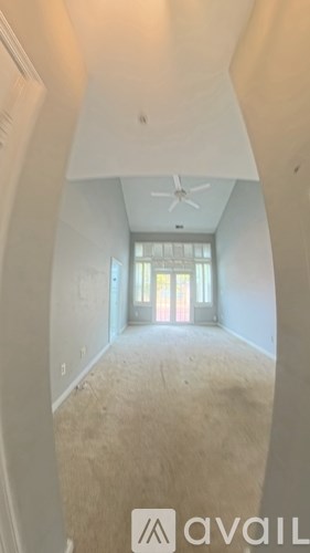 A room with a carpeted floor and a ceiling fan.