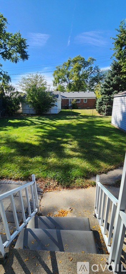 A backyard with a white fence and a house in the background.
