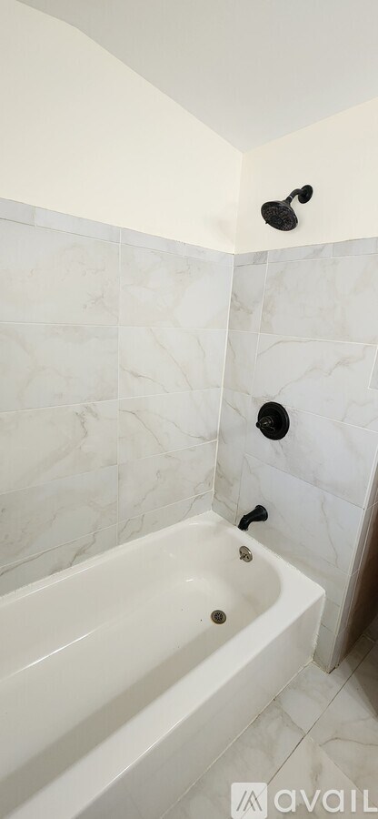 A white bathtub with a black faucet and shower head.