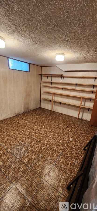 A room with a brown tiled floor and a window on the wall.