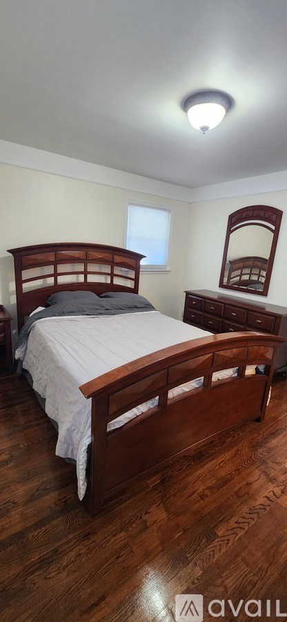 A bedroom with a bed, dresser, and mirror.