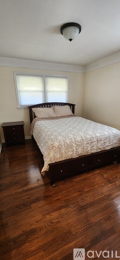 A bedroom with a bed, nightstand, and window.