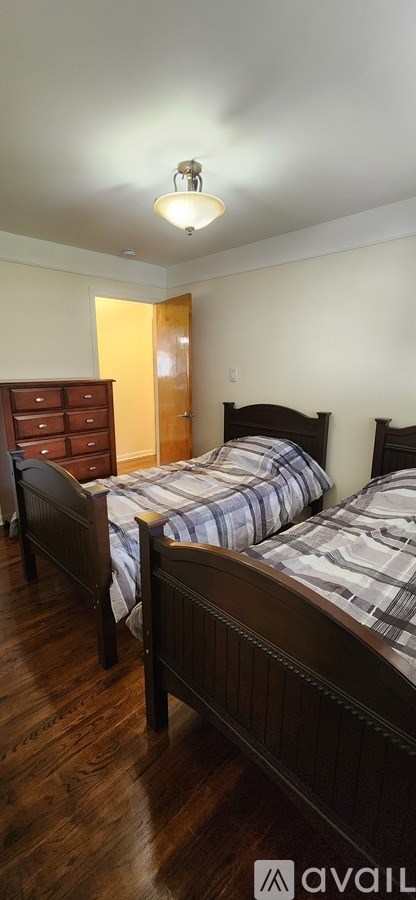 A bedroom with two beds and a dresser.