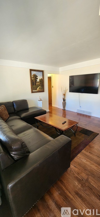 A living room with a black leather couch and a wooden coffee table.