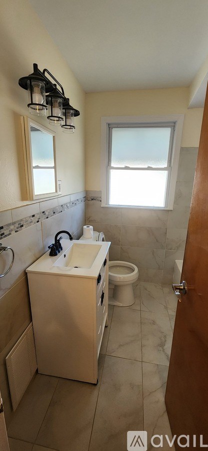 A bathroom with a toilet, sink, and mirror.