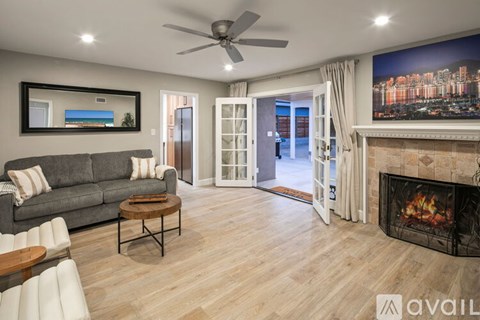 A living room with a grey couch, a coffee table, a fireplace, and a painting on the wall.