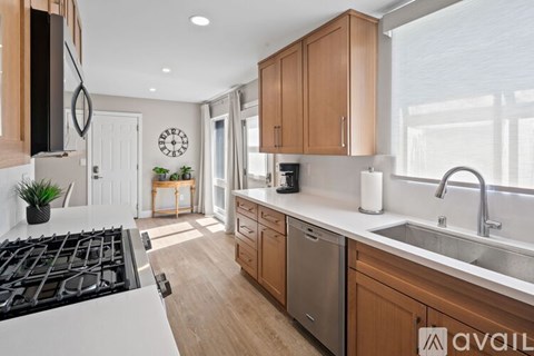 A kitchen with a white stove top and wooden cabinets.