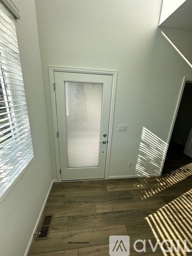 A white door with a glass window is in a room with wooden flooring.