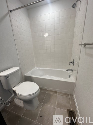 A white toilet and bathtub in a small bathroom.