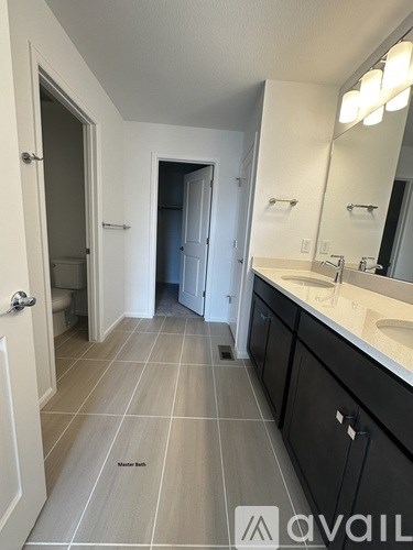 A bathroom with a mirror, sink, and tiled floor.