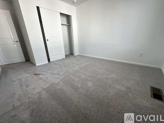 A room with a carpeted floor and two doors.