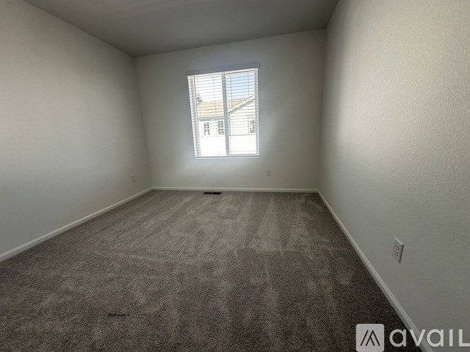 A room with a carpeted floor and a window with blinds.