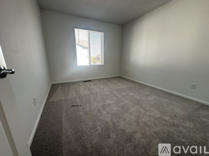 A room with a carpeted floor and a window with blinds.