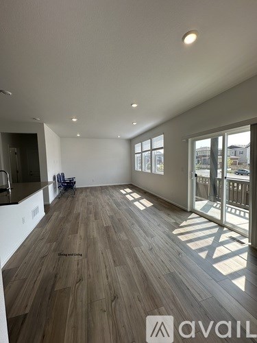 A spacious room with wooden flooring and large windows.