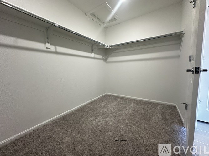 A room with white walls and a carpeted floor with a door on the right side.