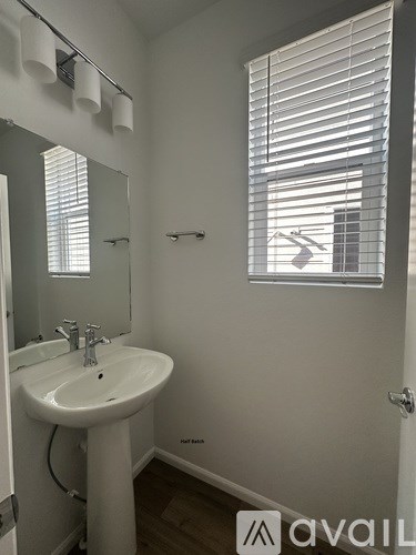 A bathroom with a sink, mirror, and window with blinds.