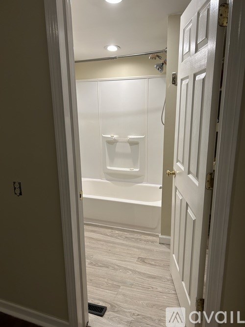 A white door is open to a bathroom with a white tub.