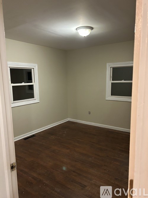 A room with wooden floors and two windows.