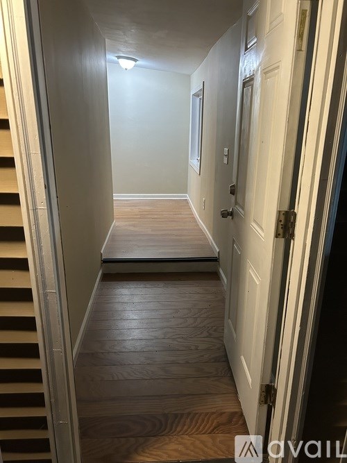 A hallway with a wooden floor and a white door.