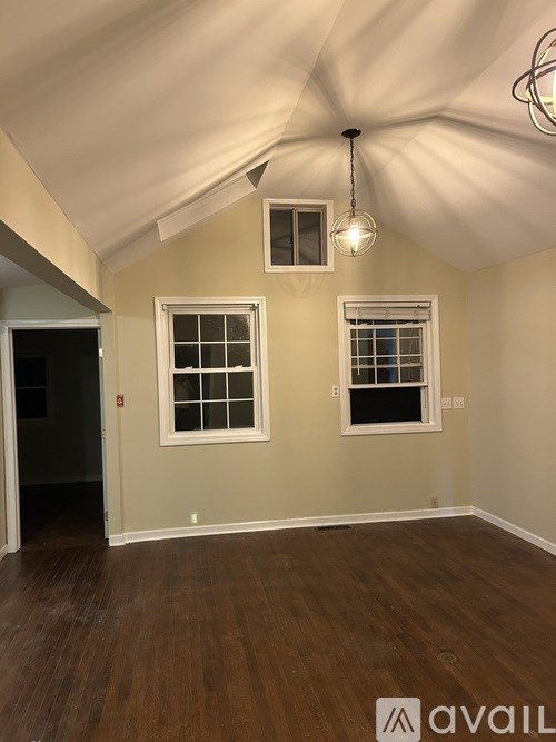 A room with wooden floors and two windows.