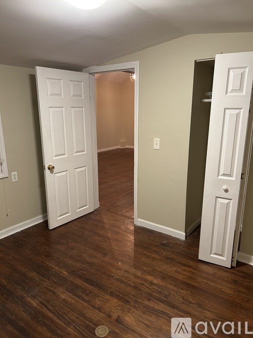 A room with a white door and a brown floor.