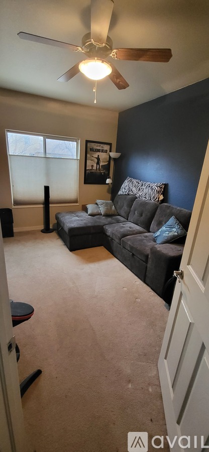 A living room with a couch and a ceiling fan.