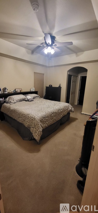 A bedroom with a bed, dresser, and ceiling fan.
